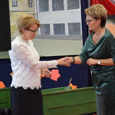 Anna Dziewior przekazuje gratulacje dyrektor szkoły, uścisk dłoni obu pań, przechylenie głowy w geście szacunku